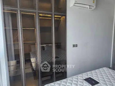 Modern bedroom with glass wardrobe and air conditioning unit, featuring a sleek design and comfortable mattress.