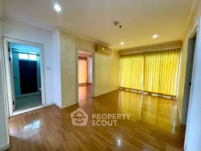 Spacious empty living room with wooden flooring and large windows with yellow curtains