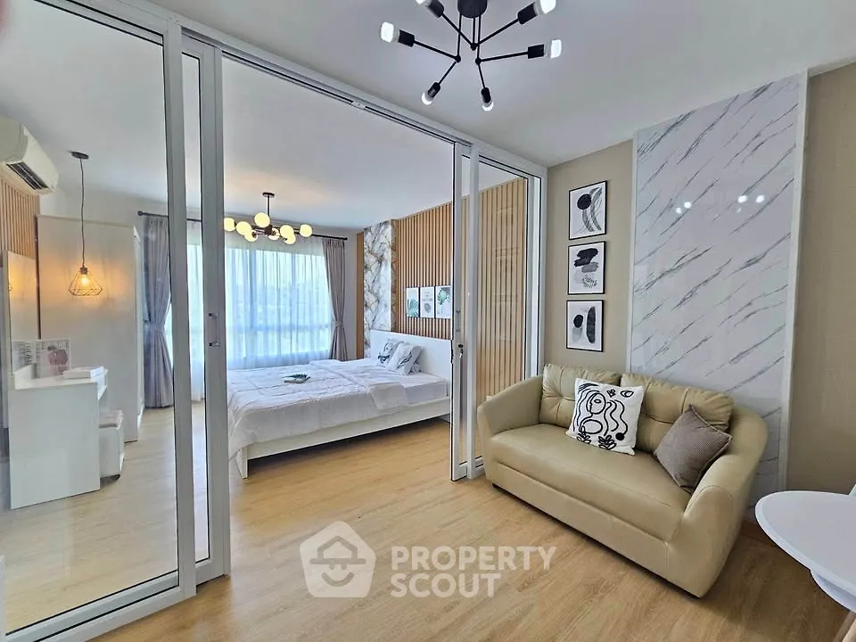 Modern bedroom with stylish decor and cozy seating area, featuring elegant lighting and large windows.