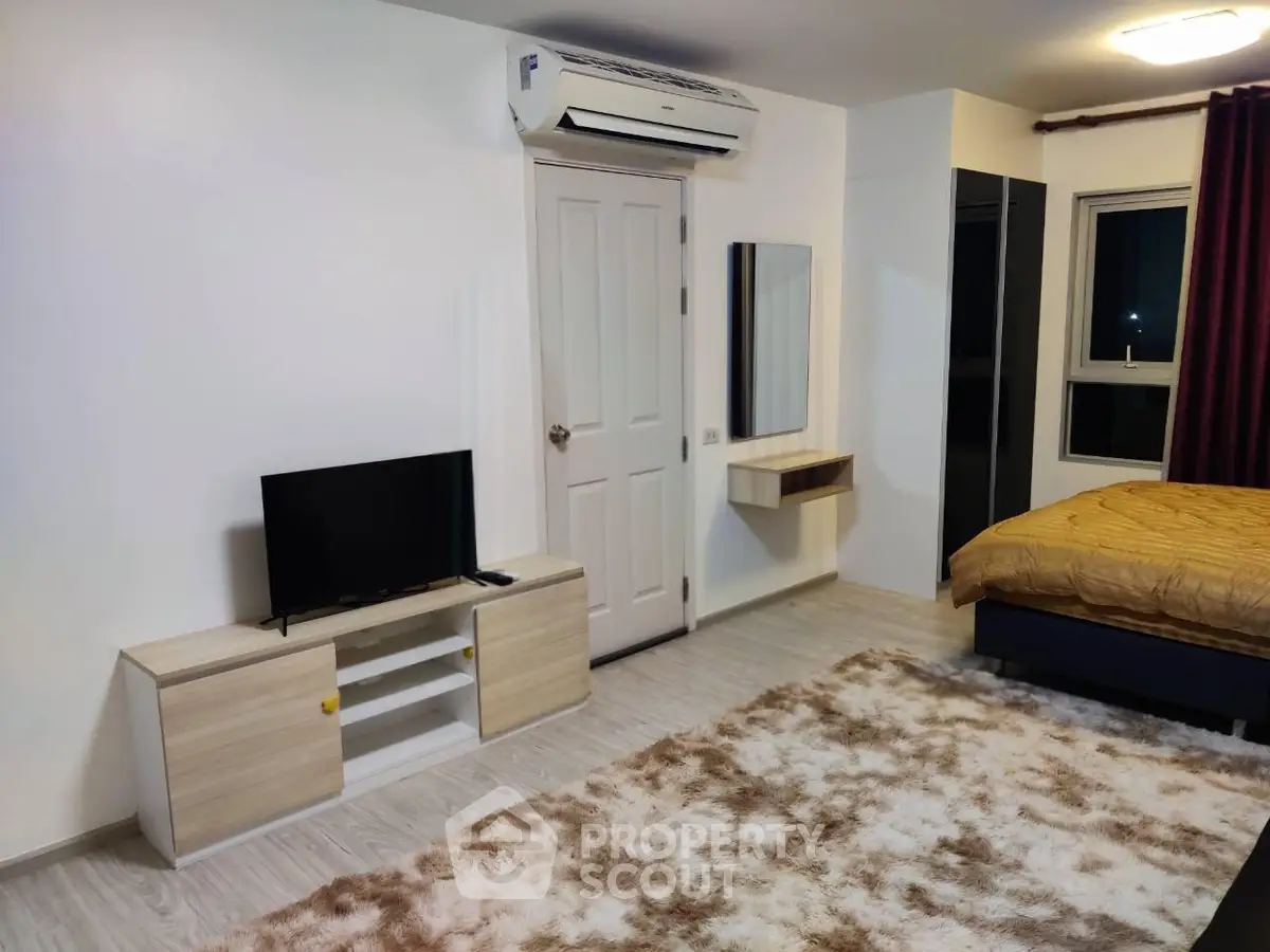 Modern bedroom with cozy decor, featuring a plush rug, TV stand, and air conditioning for ultimate comfort.