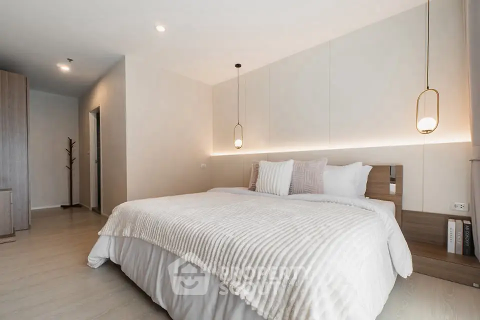 Spacious modern bedroom with elegant lighting and cozy bedding in a stylish apartment.