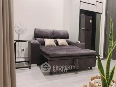 Modern living room with stylish sofa and sleek kitchen appliances in a cozy apartment setting.