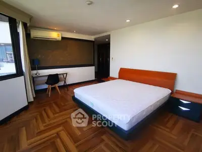 Spacious bedroom with modern design and wooden flooring, featuring a cozy bed and study area.