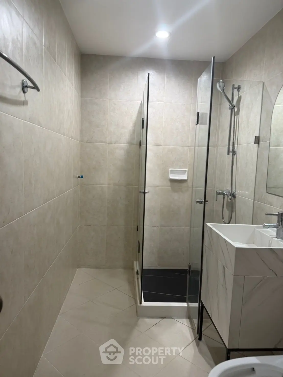 Modern bathroom with glass shower and sleek vanity in contemporary apartment.