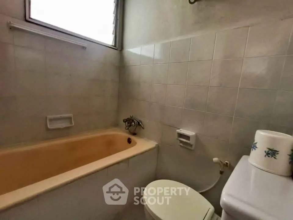 Cozy bathroom with bathtub and tiled walls, perfect for relaxation.