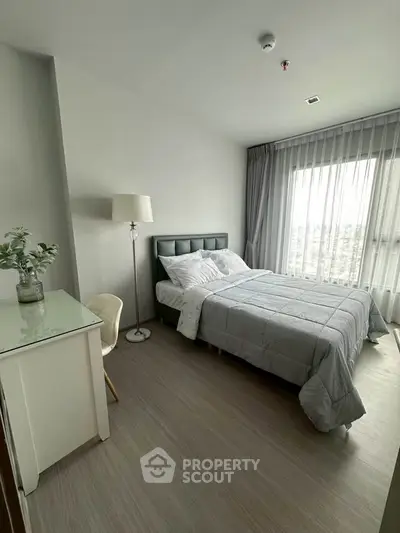 Modern bedroom with stylish decor and large window offering natural light.