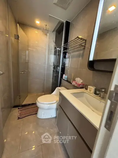 Modern bathroom with glass shower and sleek vanity in contemporary apartment.