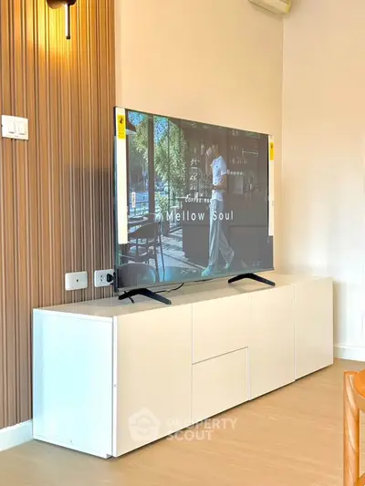 Modern living room with sleek TV stand and wall-mounted TV, featuring stylish wooden paneling and minimalist decor.