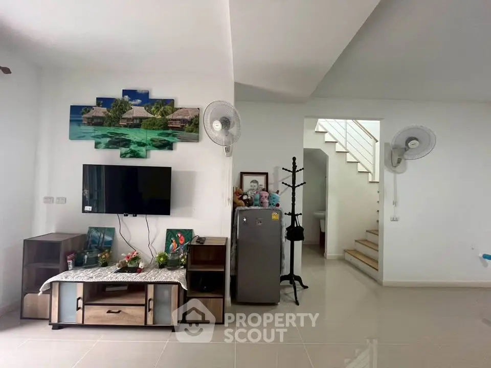 Modern living room with TV, fridge, and decorative wall art in a spacious home.
