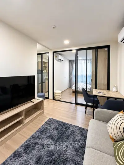 Modern living room with sliding glass doors leading to a cozy bedroom, featuring stylish decor and natural light.
