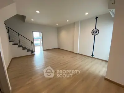 Spacious modern living room with wooden flooring and staircase, ideal for family gatherings.