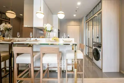 Modern kitchen with sleek design, featuring a washing machine and elegant dining area.