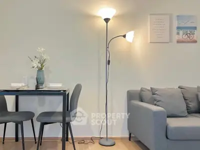 Modern living room with stylish floor lamp, cozy gray sofa, and elegant dining area with floral decor.