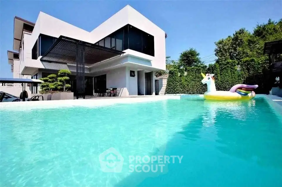 Luxurious modern home with stunning pool and unicorn float, perfect for relaxation and entertainment.