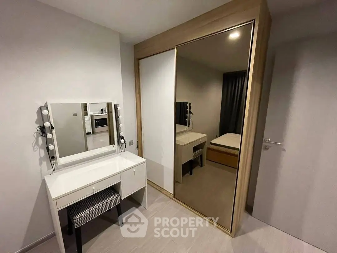 Modern bedroom with stylish vanity and mirrored wardrobe in a contemporary apartment.