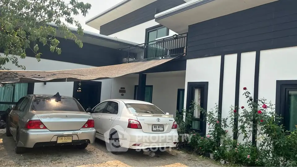 Modern two-story house with carport and garden, featuring sleek design and ample parking space.