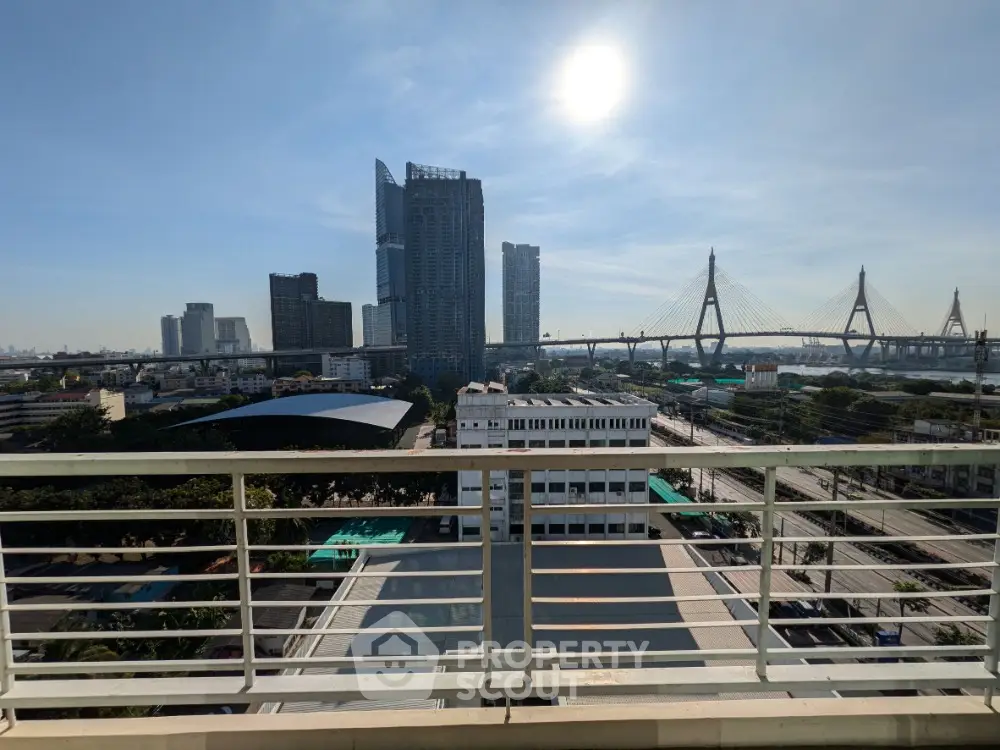 Stunning cityscape view from balcony with iconic bridge and skyscrapers under clear blue sky.
