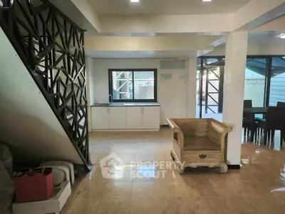 Spacious open-plan living area with modern staircase and elegant furniture.