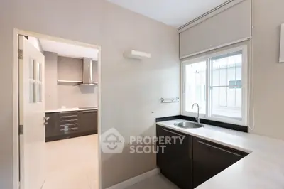 Sleek modern kitchen with built-in stainless steel oven, ample counter space, and a large window allowing for plenty of natural light.