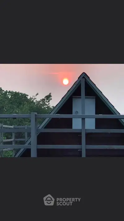 Charming A-frame cabin with sunset view and lush greenery.