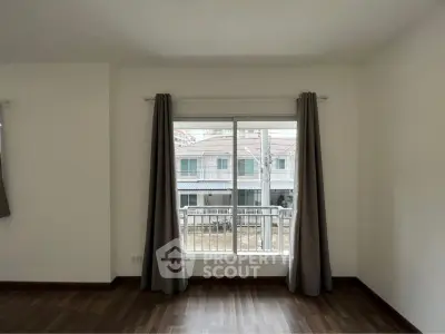 Spacious and well-lit living room with large windows and elegant dark wooden flooring, offering a serene view of the neighborhood.
