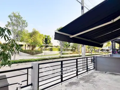 Modern residential exterior with sleek black awning and lush greenery in a serene neighborhood.