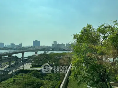 Stunning cityscape view with lush greenery and river, perfect for urban living.