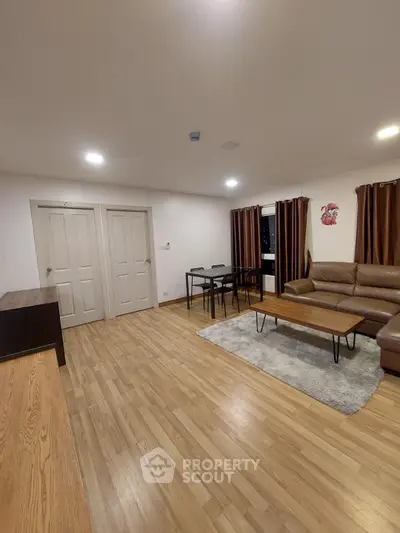 Spacious living room with wooden flooring and modern furniture in a cozy apartment.