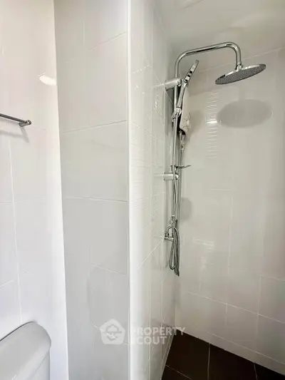 Modern bathroom with sleek shower fixtures and white tiled walls, offering a clean and contemporary design.