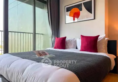 Modern bedroom with stylish decor and balcony view, featuring cozy bedding and contemporary artwork.