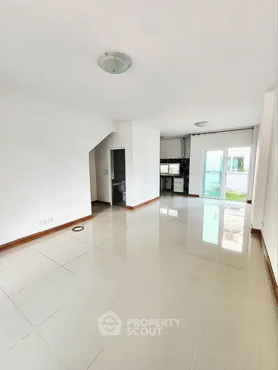 Spacious open-plan living area with glossy tiled floors and abundant natural light.