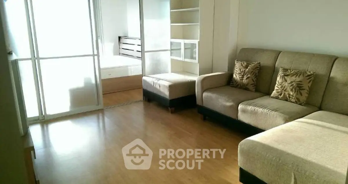 Spacious living room with modern sofa and sliding glass doors leading to a bedroom.