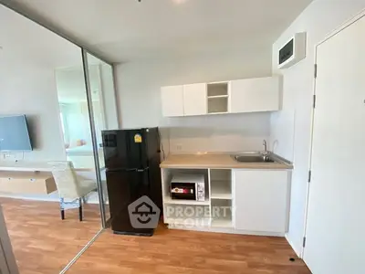 Modern compact kitchen with sleek black fridge and microwave in a stylish apartment