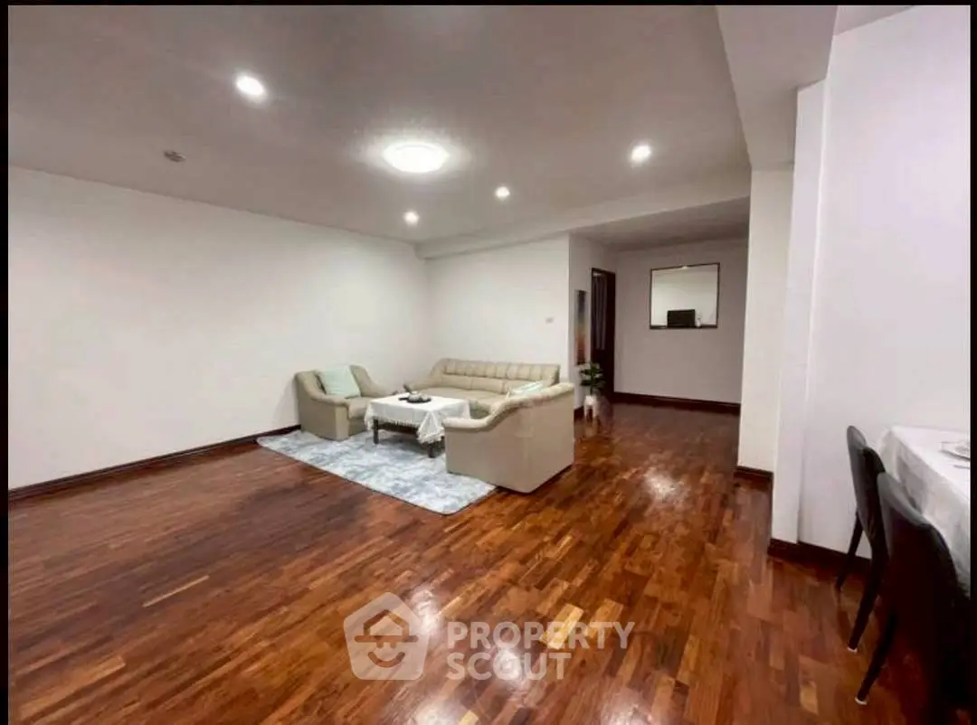 Spacious living room with elegant wooden flooring and cozy seating area.