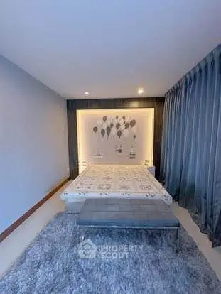 Modern bedroom with stylish decor and cozy ambiance, featuring a plush rug and elegant curtains.