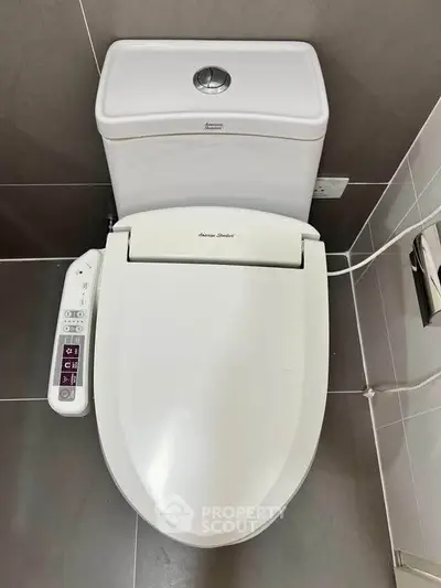 Modern bathroom with high-tech toilet featuring bidet controls and sleek design.