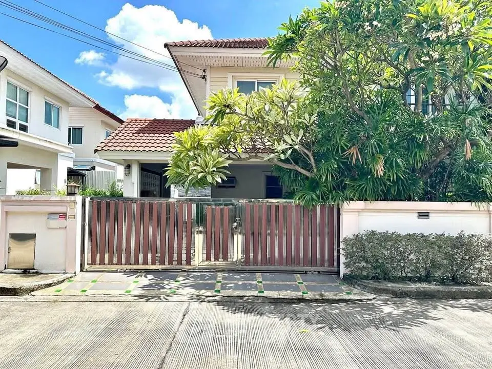 Charming suburban house with lush greenery and gated entrance, perfect for family living.