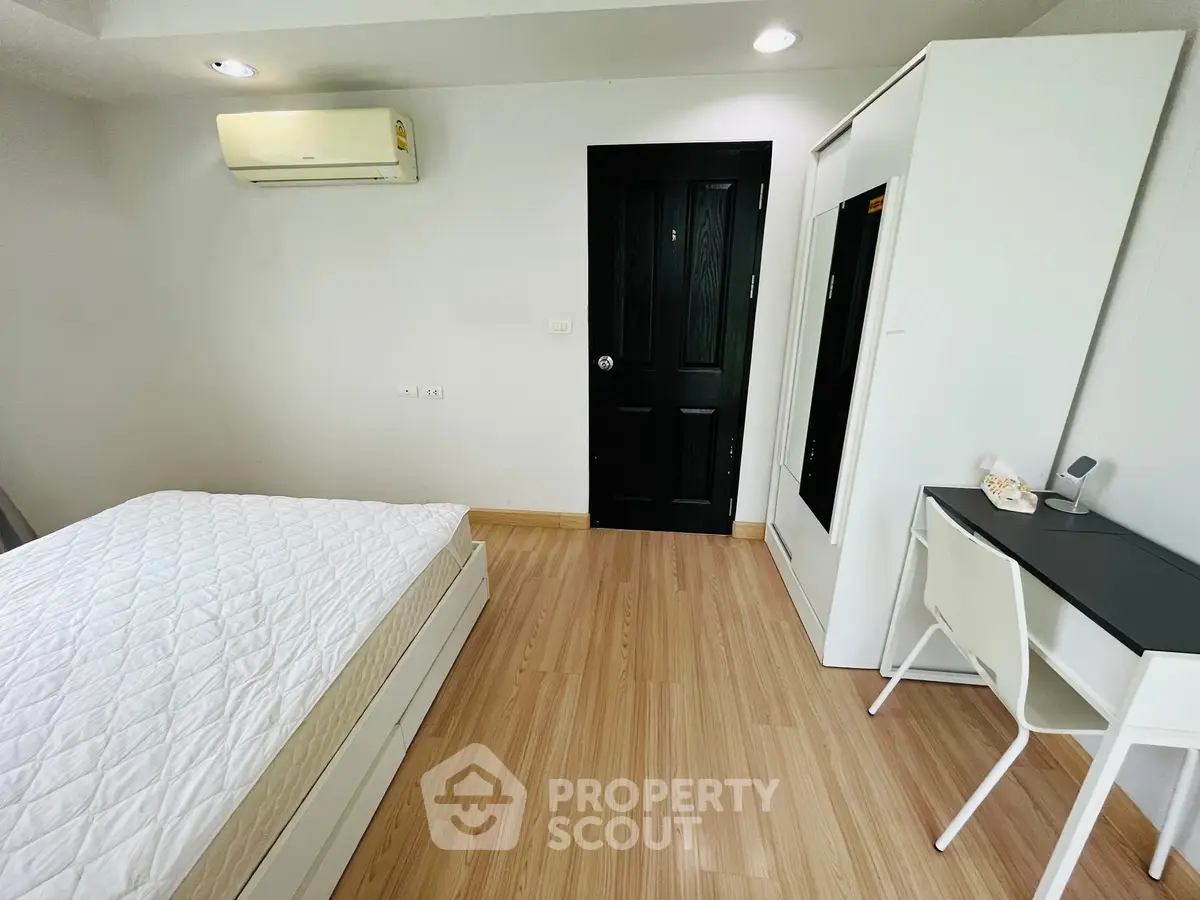 Modern bedroom with minimalist design, featuring a bed, desk, and wardrobe in a bright space.