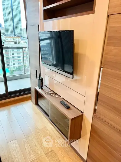 Modern living room with sleek TV setup and city view from balcony.