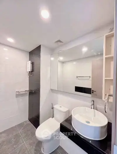 Modern bathroom with sleek fixtures and large mirror in a contemporary apartment.