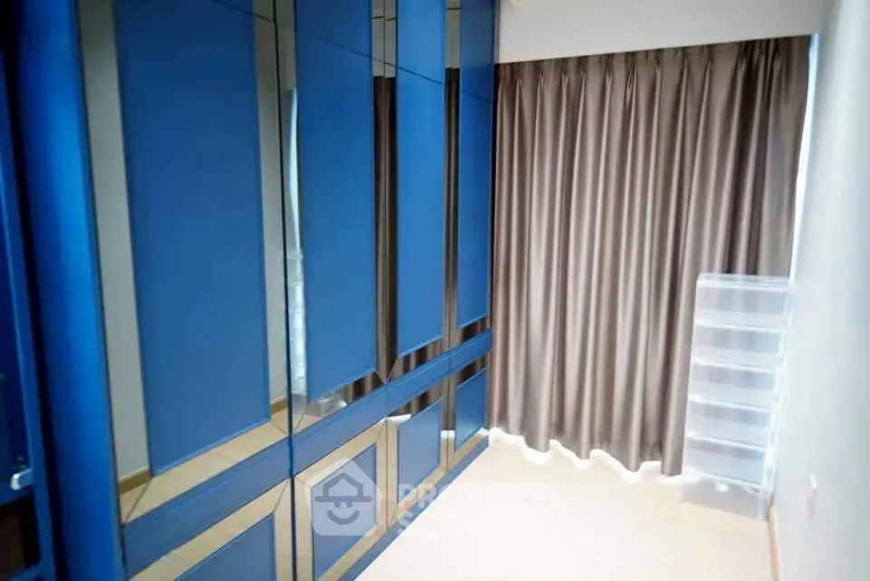 Spacious bedroom with sleek blue wardrobes and elegant curtains