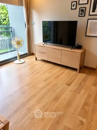 Modern living room with wooden flooring, TV stand, and balcony view.