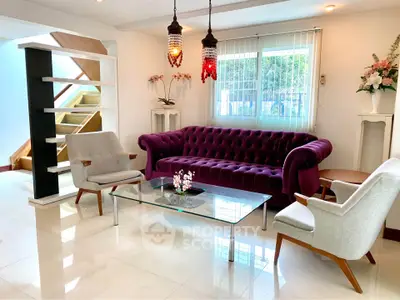 Elegant living room with plush purple sofa, modern chairs, and stylish decor in a bright, airy space.