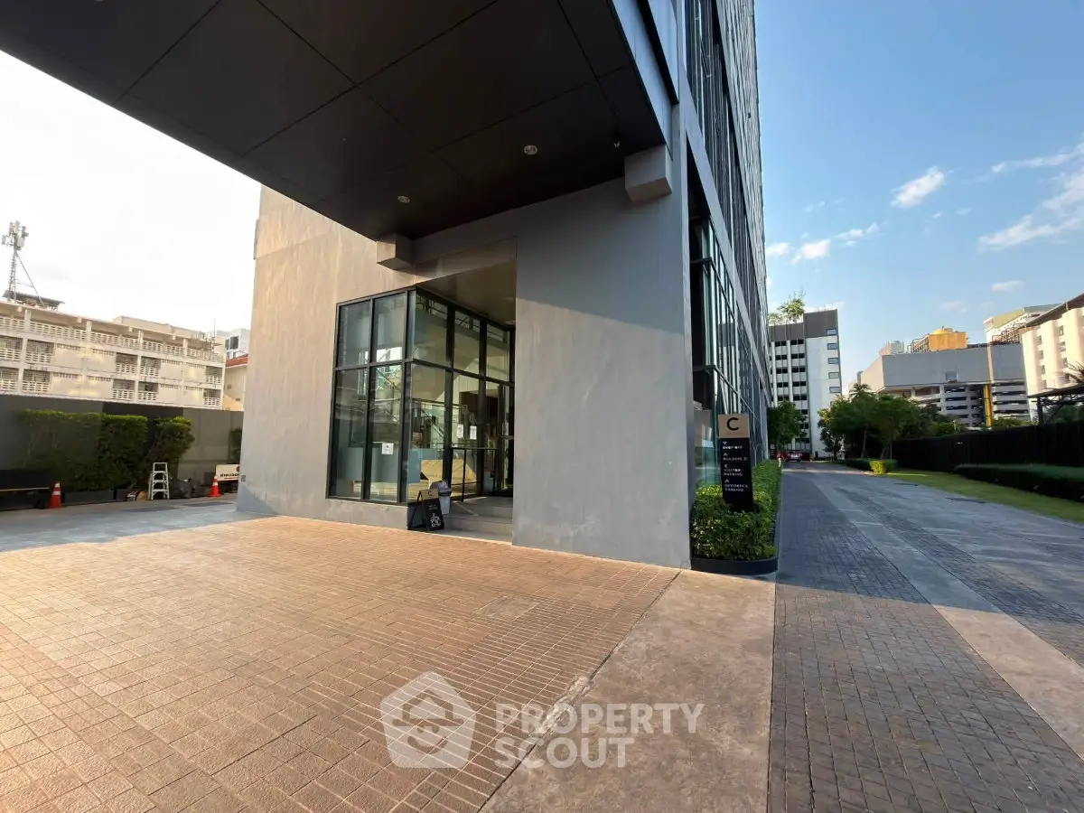 Modern building entrance with sleek glass doors and paved walkway in urban setting.
