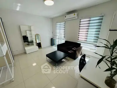 Modern living room with sleek furniture and natural light, featuring air conditioning and stylish blinds.