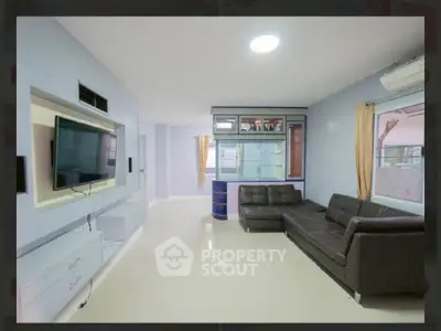 Spacious modern living room with sleek design and large TV, perfect for relaxation and entertainment.