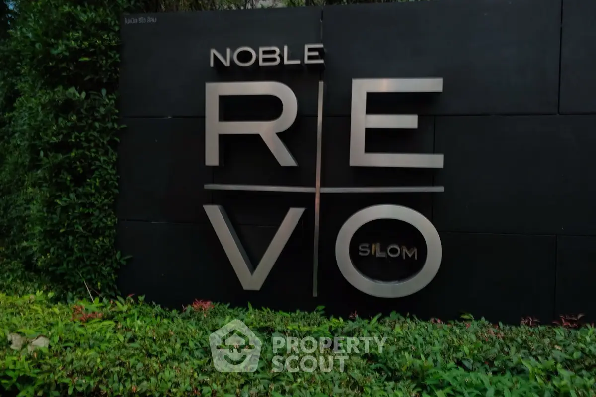 Modern exterior signage of Noble Revo Silom with lush greenery