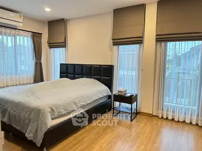 Spacious bedroom with modern decor and large windows for natural light.