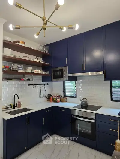 Modern kitchen with navy cabinets, open shelving, and sleek appliances in a stylish home.