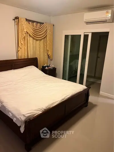 Cozy bedroom with elegant drapes and air conditioning, featuring a sleek wooden bed frame.